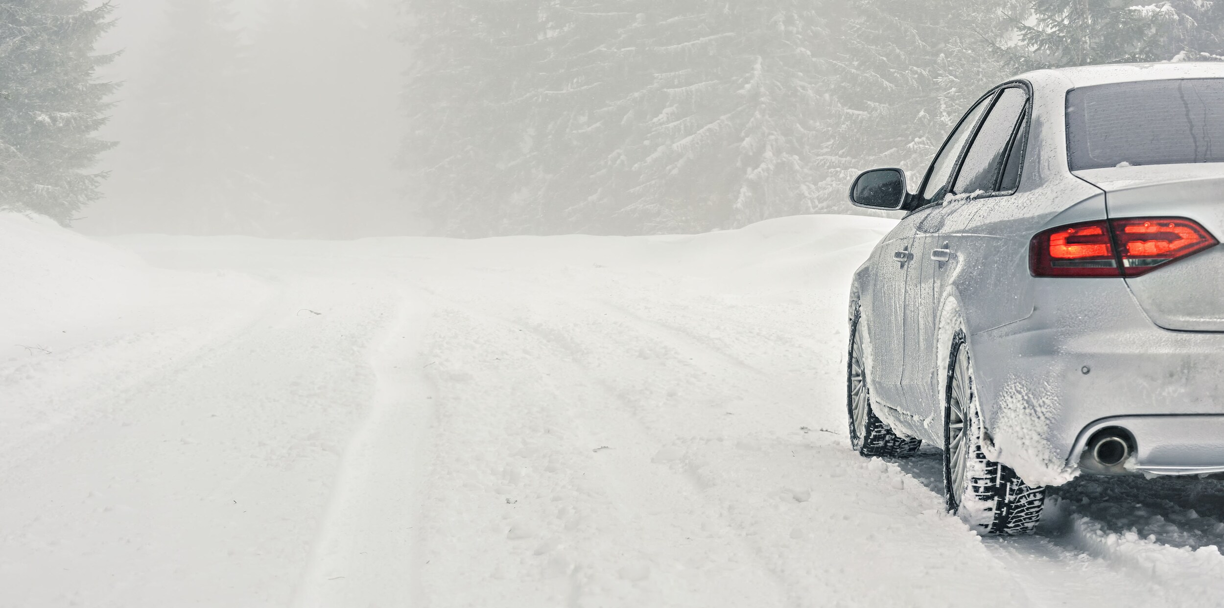 FWD%20Cars%20Silver%20Car.jpg A sliver car driving slowly in a blizzard.