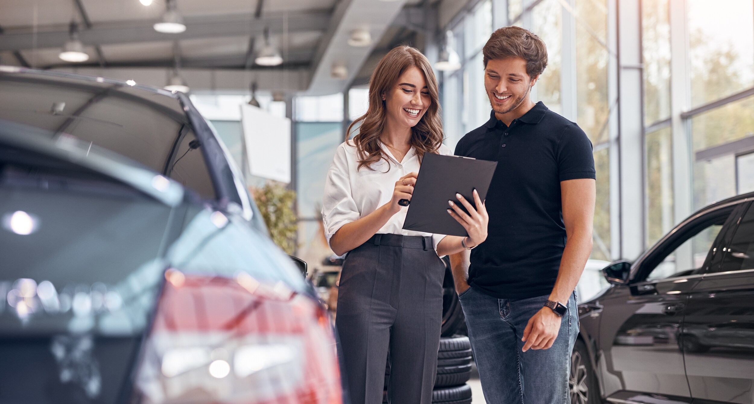 AdobeStock_412100707.jpeg Two people discussing the details of a new car.