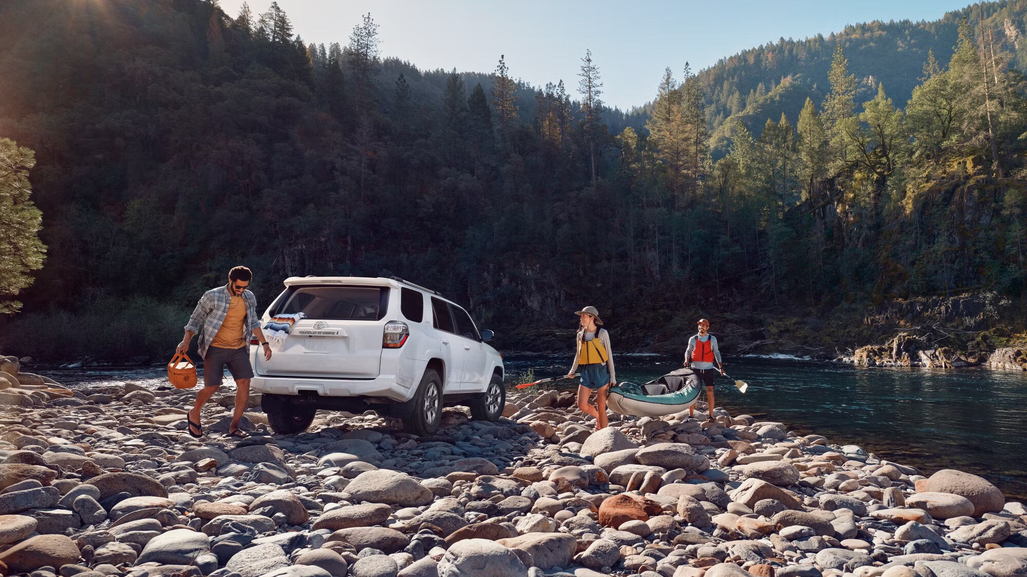 2024%204Runner.jpg A white 2024 Toyota 4Runner on a rocky shore next to a river while a family carries their fishing gear back to the vehicle.