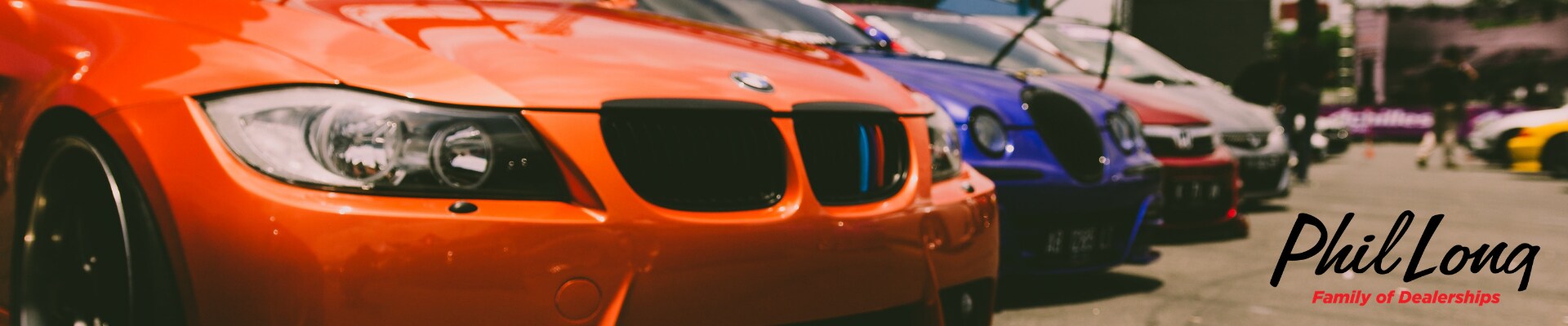 Best used cars for resale value in Colorado Springs at Phil Long Dealerships.png Close up view of an orange used BMW car at the front of a line of used cars on display