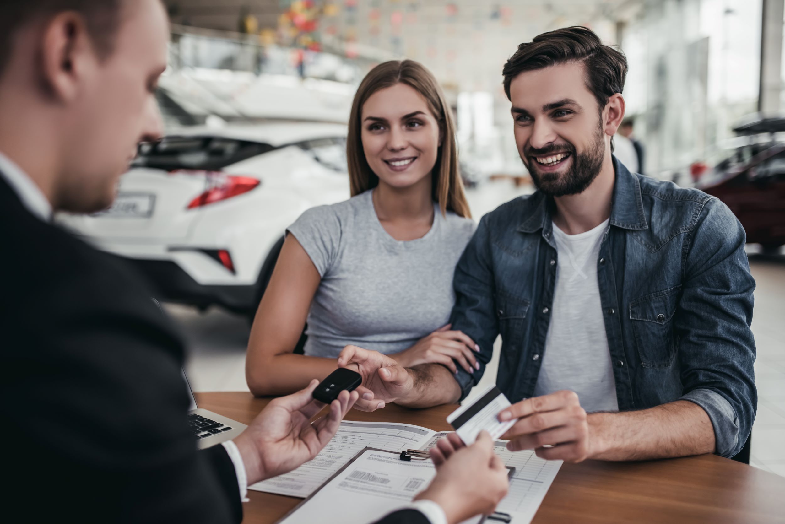 AdobeStock_162230515.jpeg A family speaking with a car salesman at a dealership.
