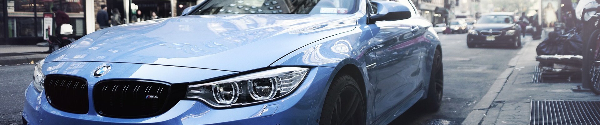 How to buy used cars in Colorado at Phil Long Dealerships.png Close up look at the front exterior of a used blue BMW M6 car parked on a busy city street