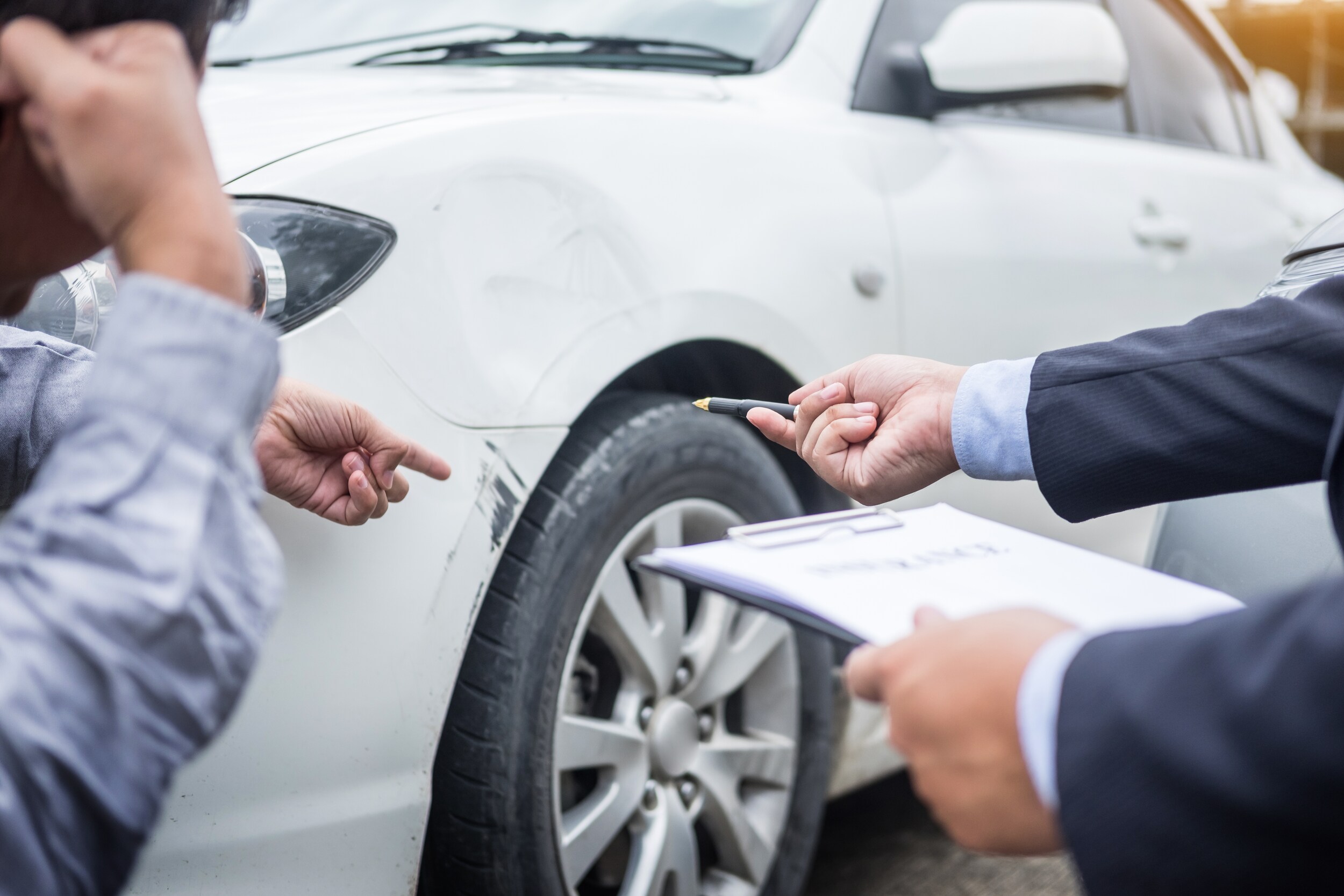 trading in a car-8.jpeg A man pointing to a scratch on a car