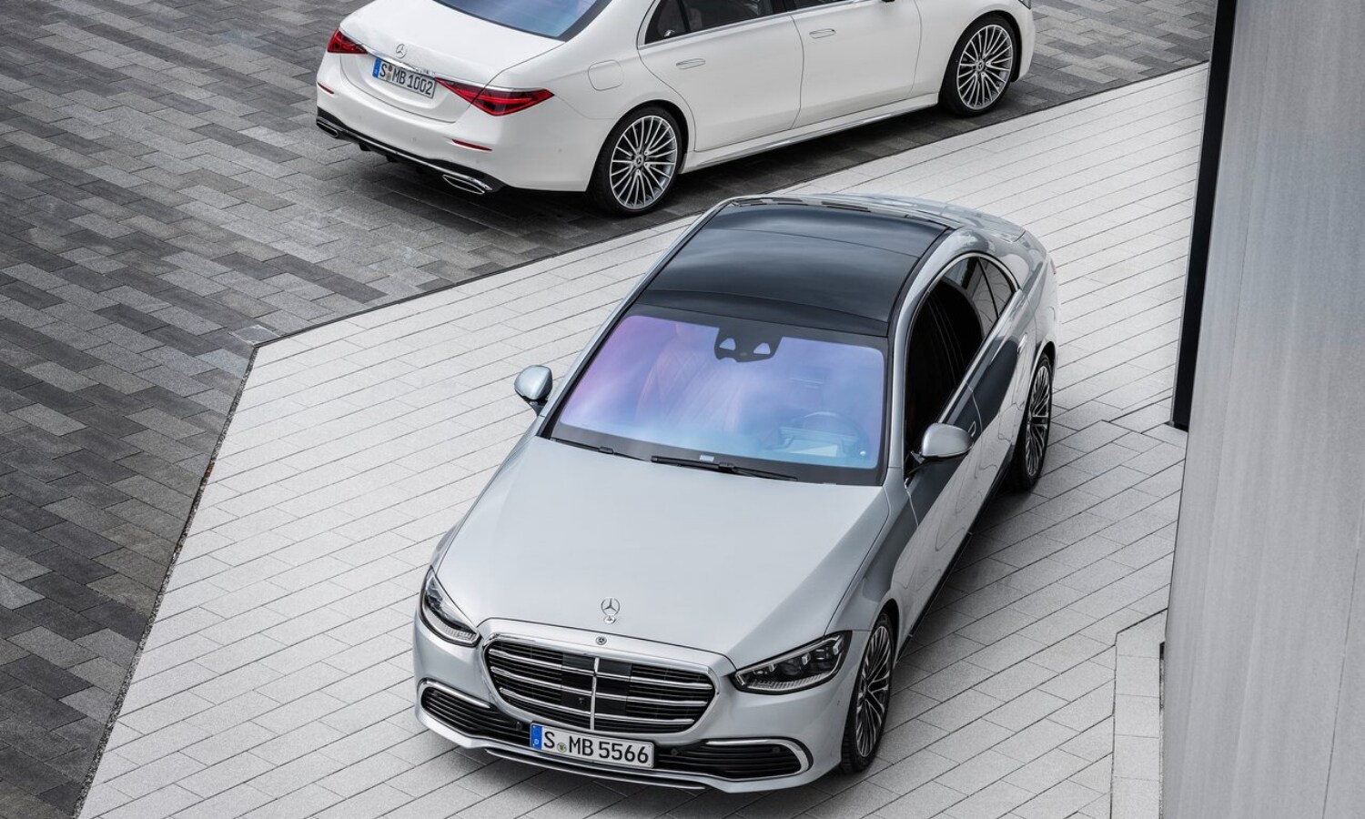 New 2021 Mercedes-Benz S-Class Sedan Exterior (1).png Aerial view of two 2021 Mercedes-Benz S-Class sedans showing front and rear exterior design