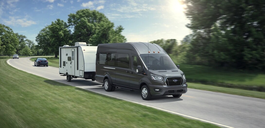2022 Ford Transit3 A green 2022 Ford Transit Driving on a highway with a Travel Trailer being towed behind it
