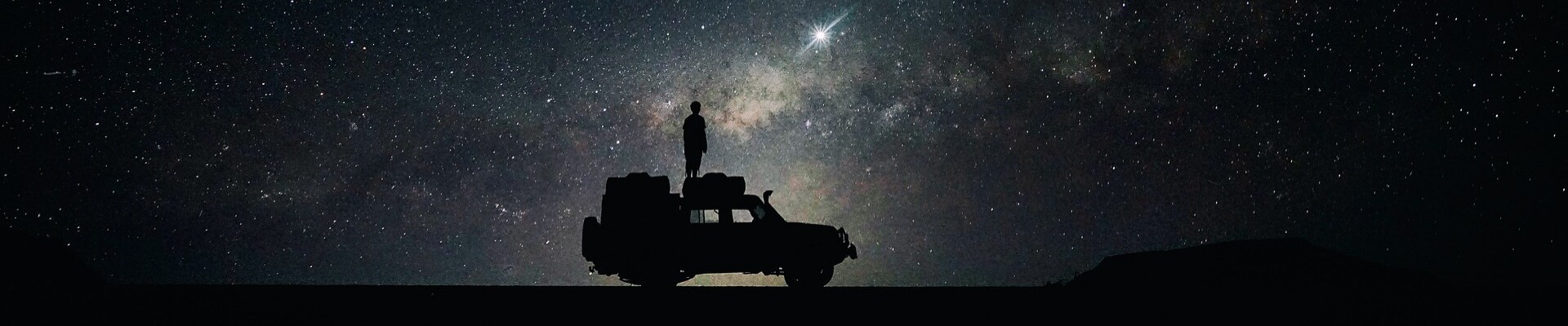 Best used car warranties in Colorado Phil Long Dealerships.png Night time sky full of stars with the silhouette of a man standing on his SUV