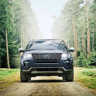 2019 Ford Explorer at Phil Long Ford Denver.png The
front view of a dark blue 2019 Ford Explorer driving down a dirt path splitting
the tall green forest in the background