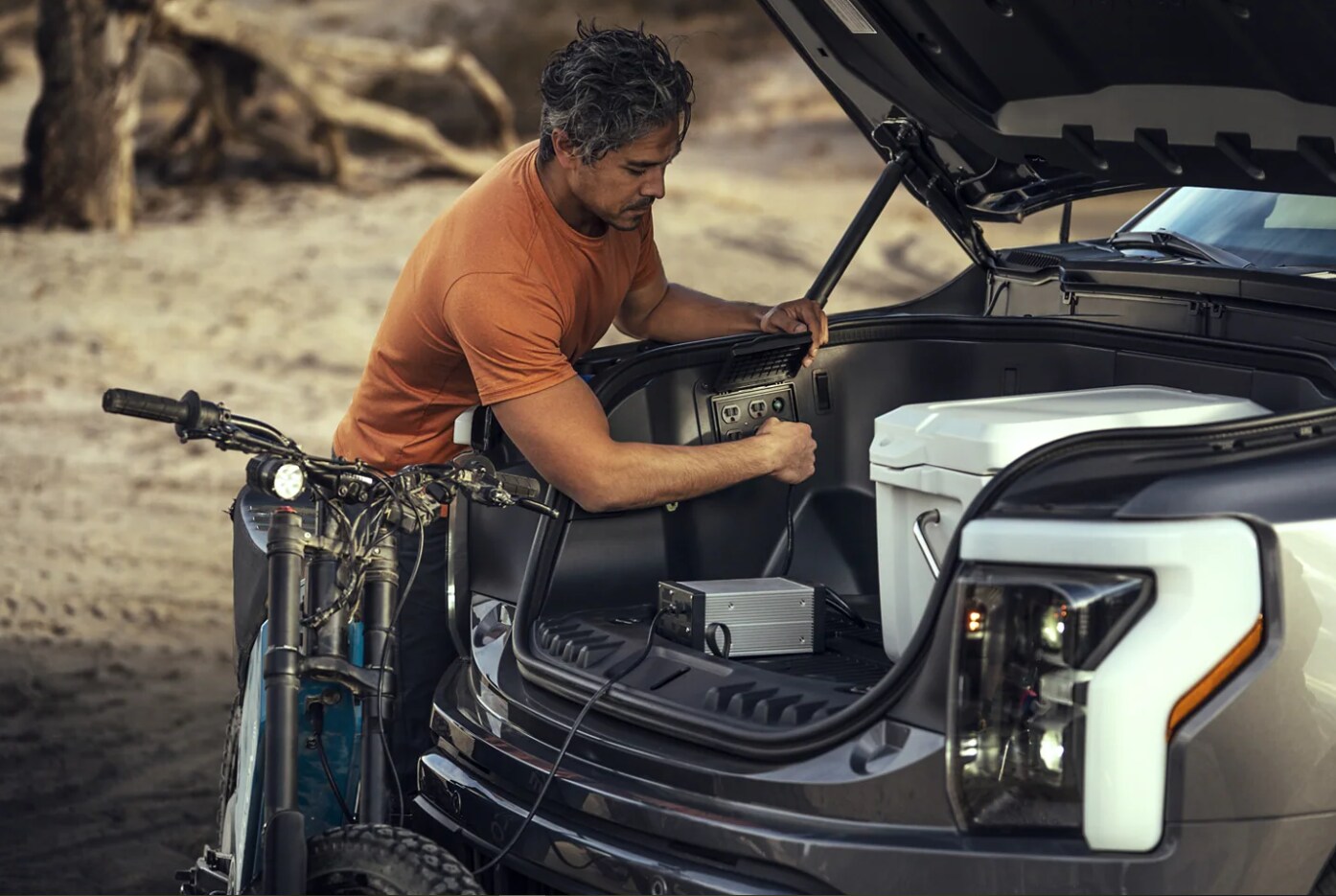 2023-ford-f-150-lightning-6.PNG A man charges a battery in the front trunk or frunk of a 2023 Ford F-150 Lightning