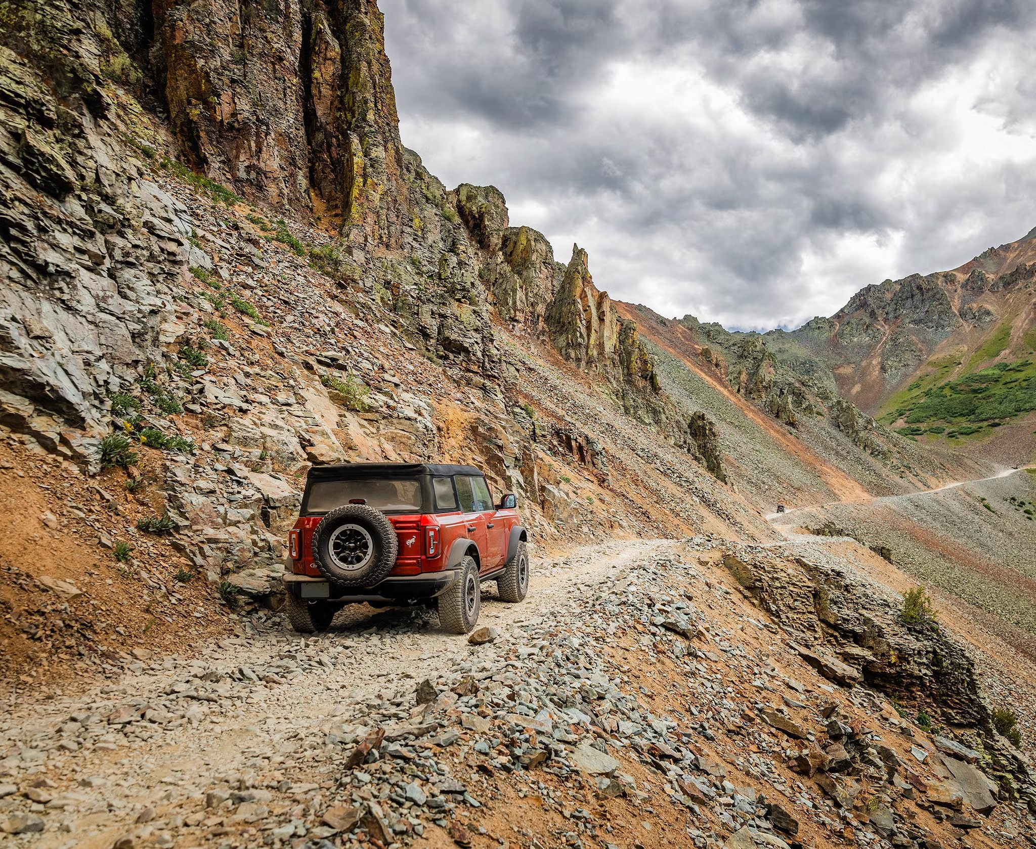 Red Ford Bronco climbing a rocky mountain trail