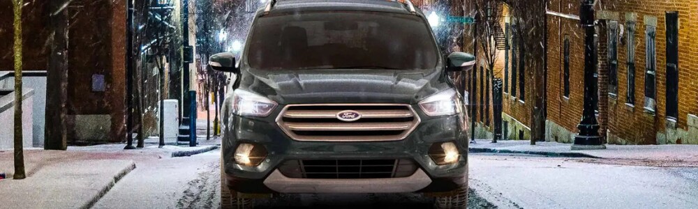 2019 Ford Escape models in Denver at Phil Long Ford Denver.png Front view of a dark green 2019 Ford Escape driving on an uphill city street in Denver through the snow with ease