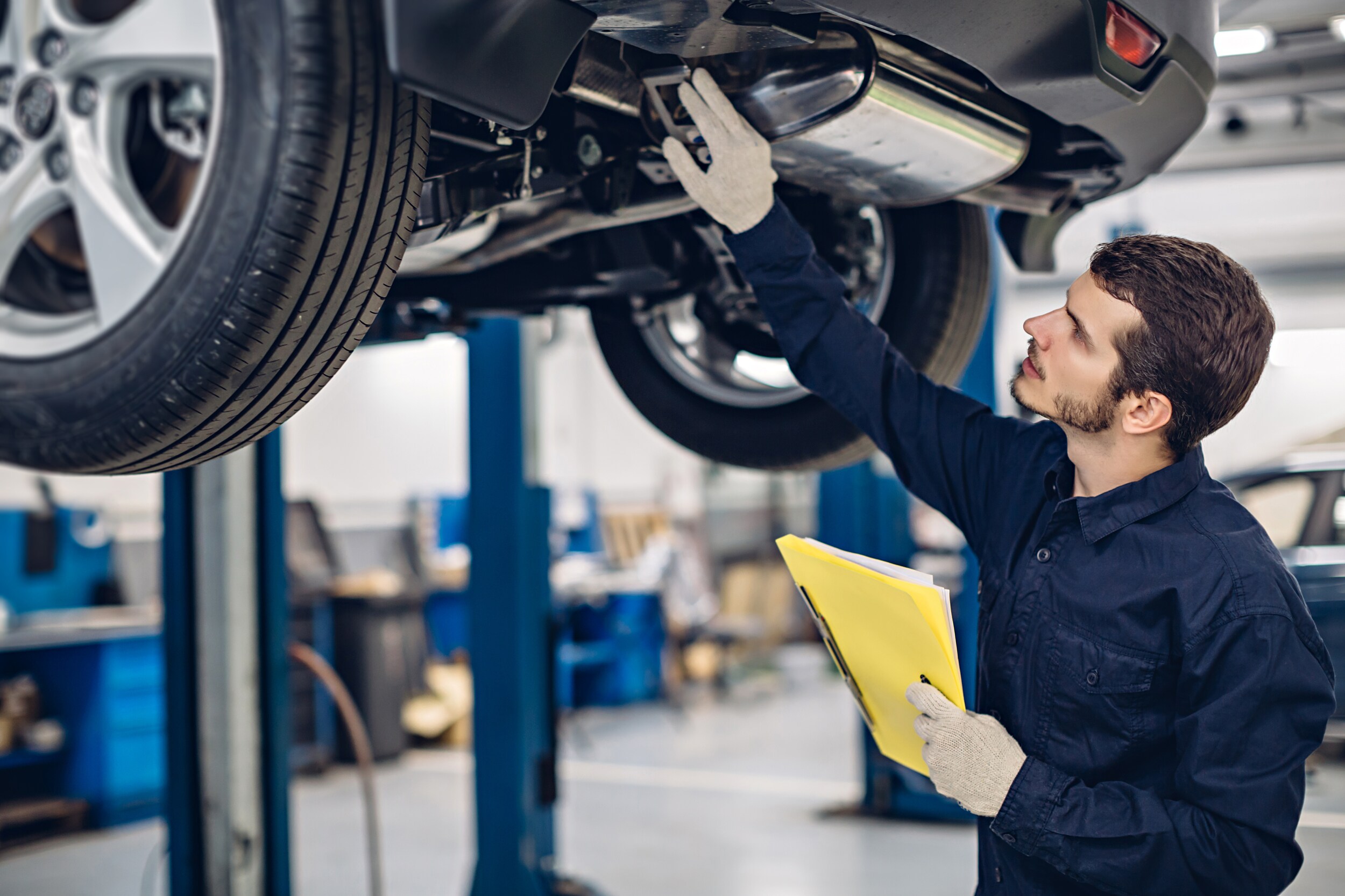 car inspection.jpeg A technician inspects the undercarriage of a car in a repair center