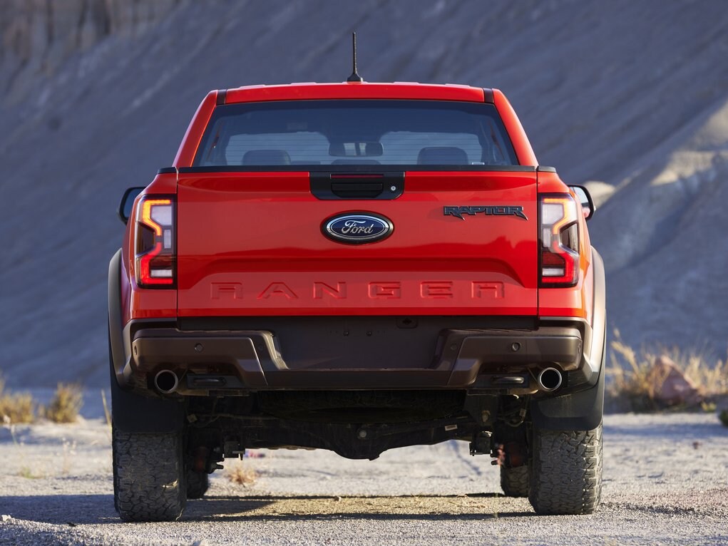 2022-Ford-Ranger-Raptor-!.PNG The back of a red 2023 Ford ranger raptor driving on a dessert road