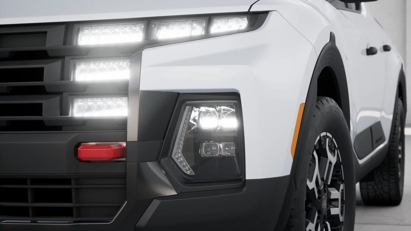 XRT dark front grille and projector bi-LED headlight on a white 2026 Hyundai Santa Cruz XRT
