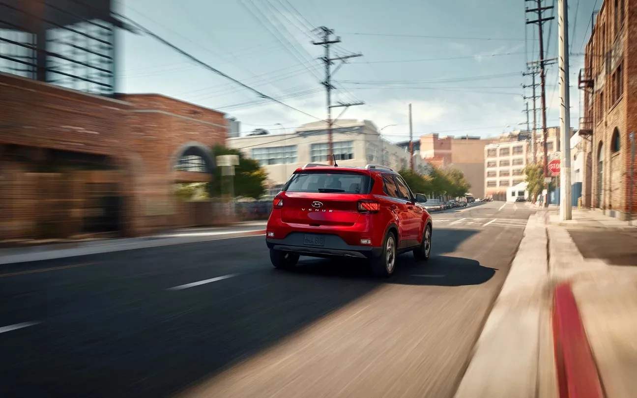 Red Hyundai Venue driving down a city street