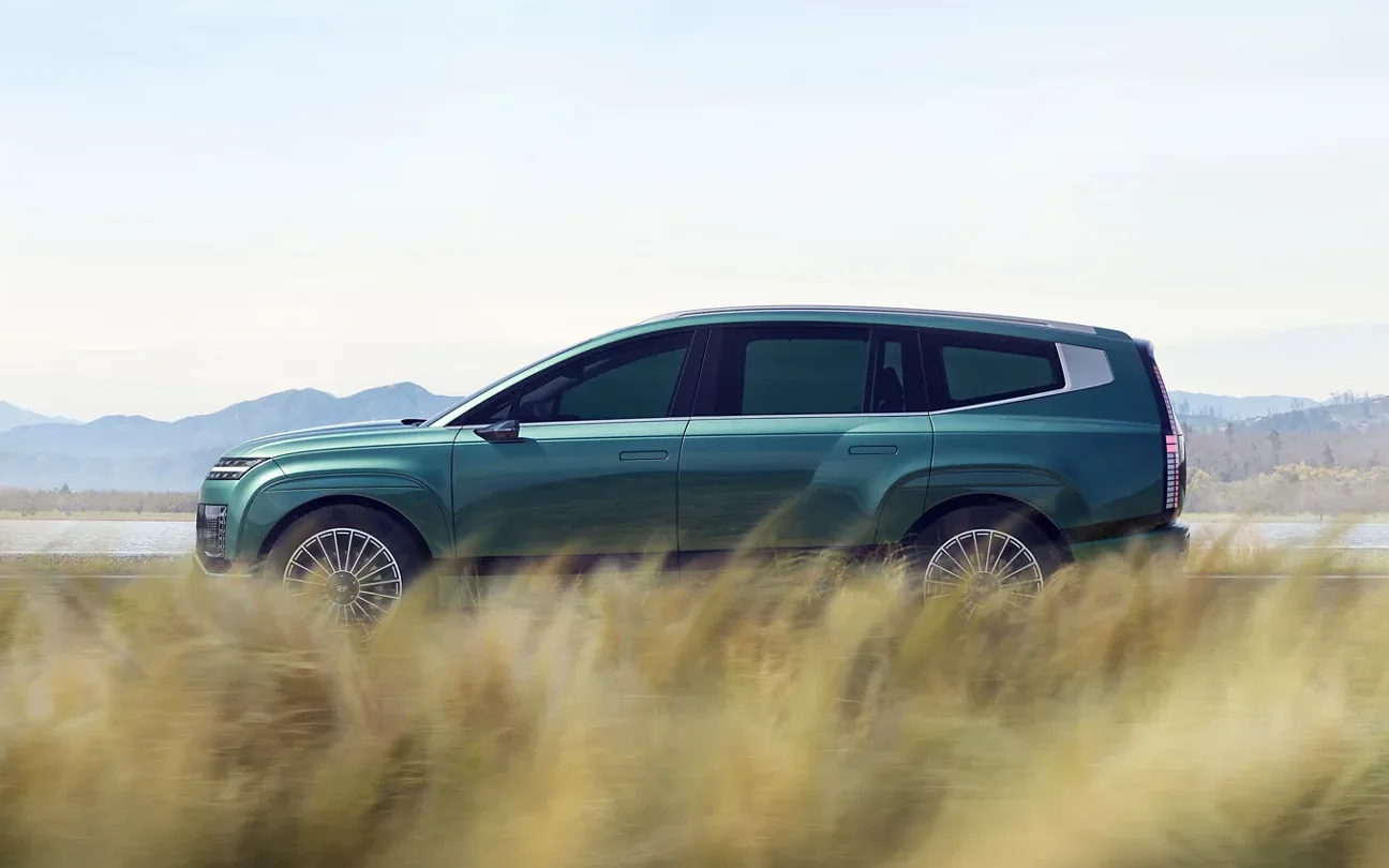 Side profile of a green 2026 Hyundai Ioniq 9 driving past mountains