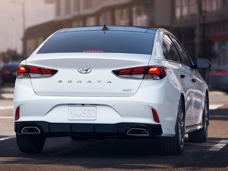 Back side Exterior of a white 2019 Hyundai Sonata waiting at a stoplight intersection