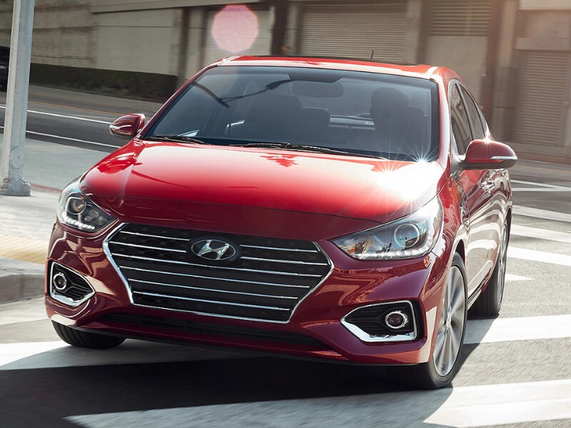 2020 Hyundai Accent red color in motion turning city corner sun reflection hood