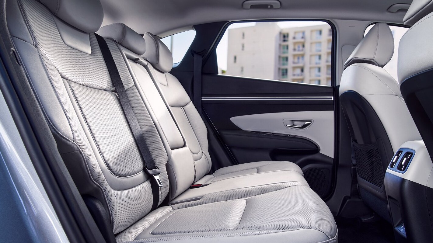 2022-Hyundai-Tucson-04.PNG View of the interior, back seat of the Hyundai Tucson that is all light gray with accents of black, has 3 seats and a pull-down center console