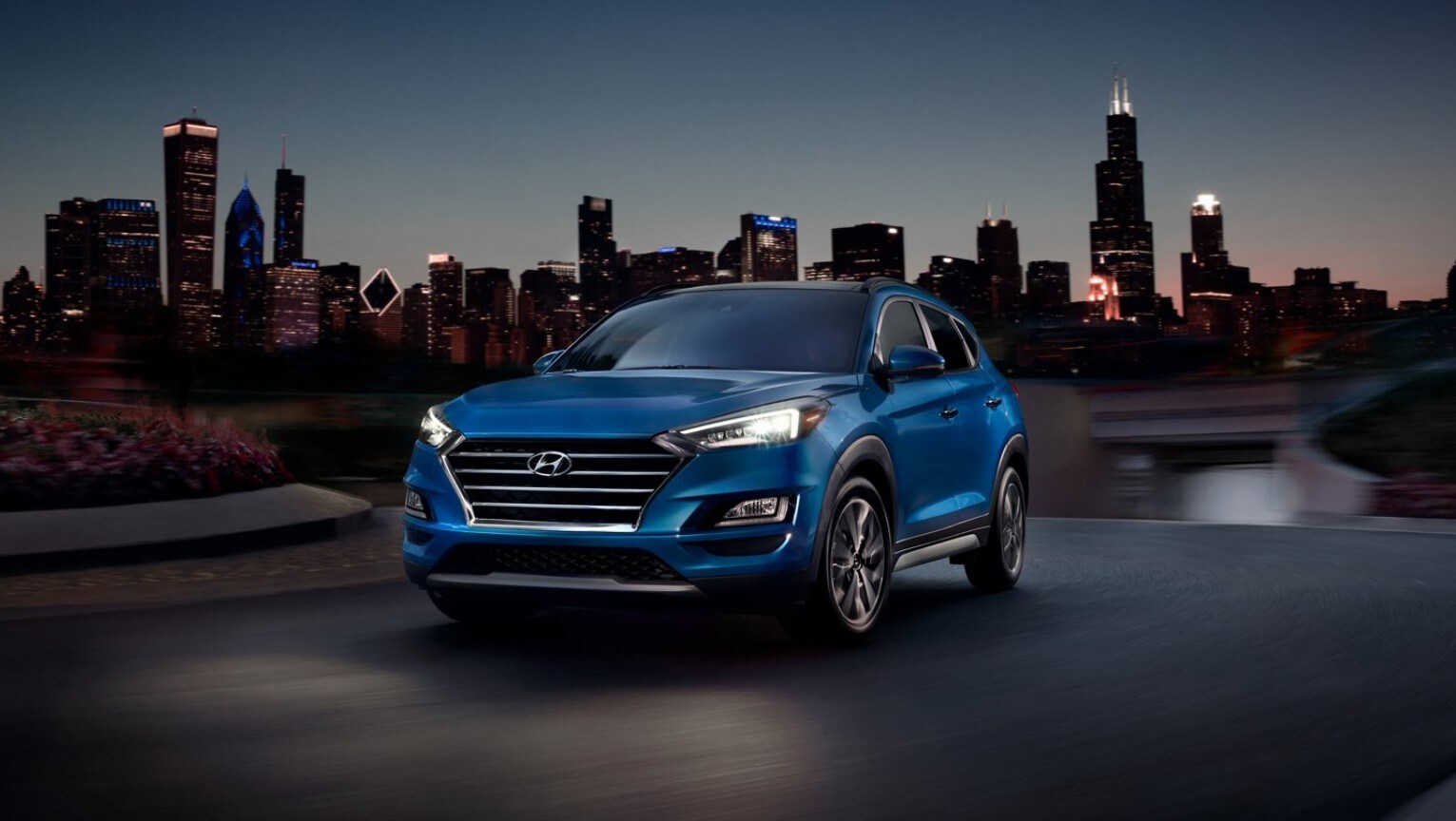 2021-hyundai-tucson-13.jpg A Hyundai Tucson parked at dusk with a city in the background