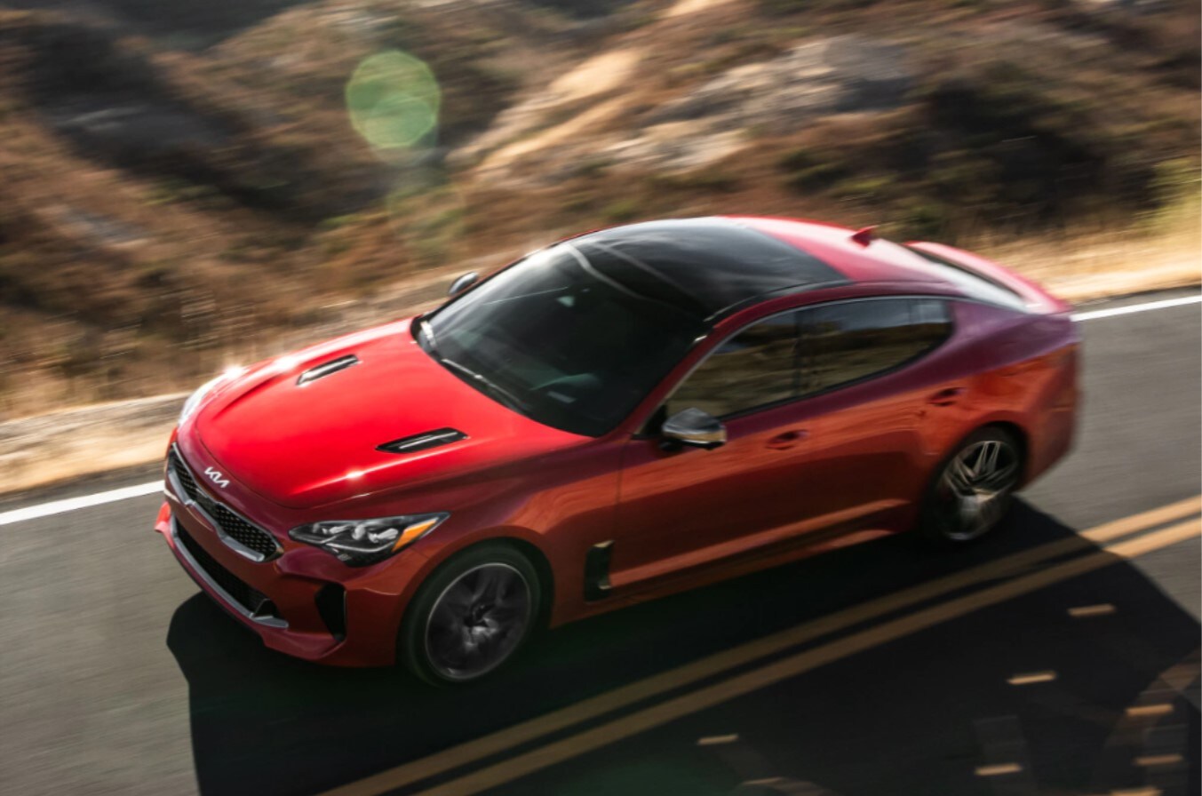 2022-kia-stinger-03.jpg Aerial view of a new Kia Stinger in red driving on a scenic road