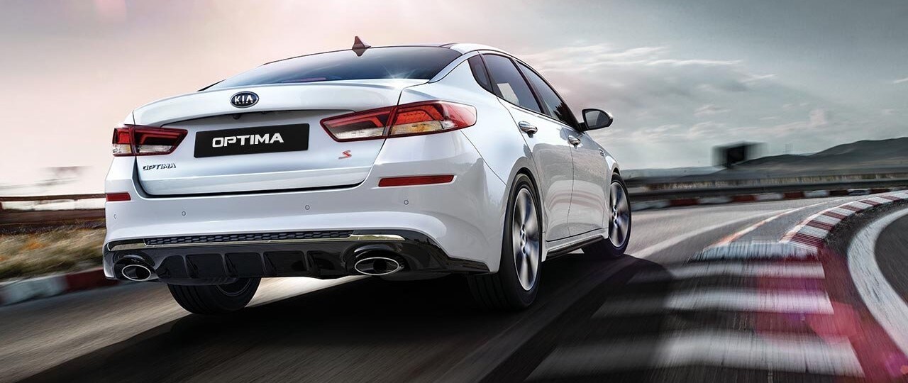 2020-kia-optima-phil-long-kia-colorado-springs-co.jpg A closeup of a white 2020 Kia Optima from the bumper side drive on a race track