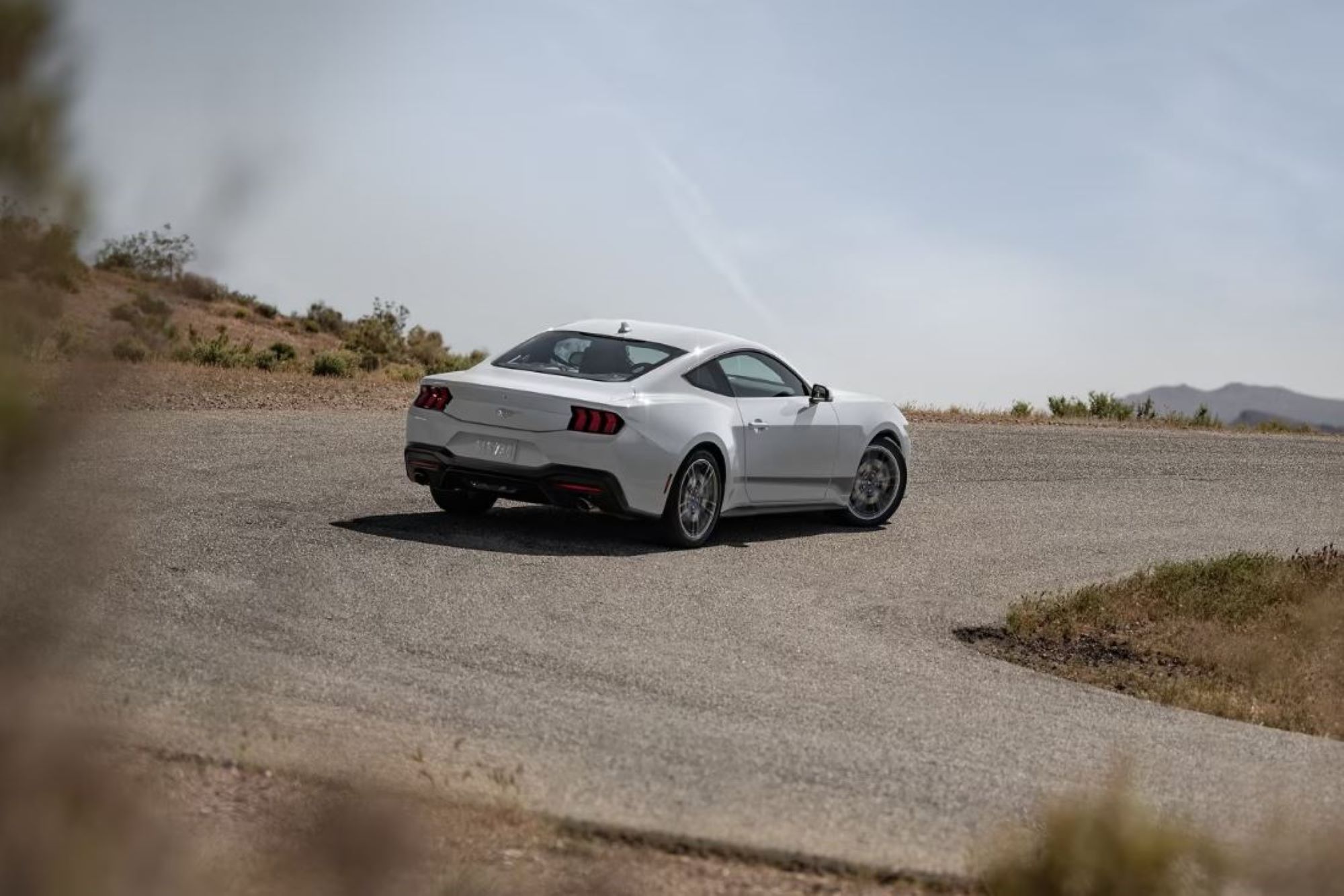 1 Mustang White.JPG A New white Ford Mustang driving through a racetrack while drifting around a corner.