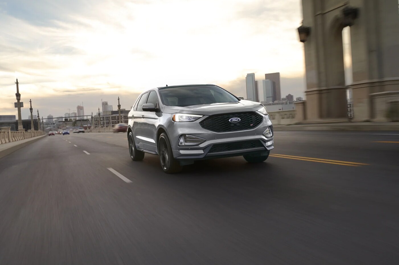 2023-ford-edge-2.PNG A gray 2024 Ford Edge drives toward the viewer on a city street