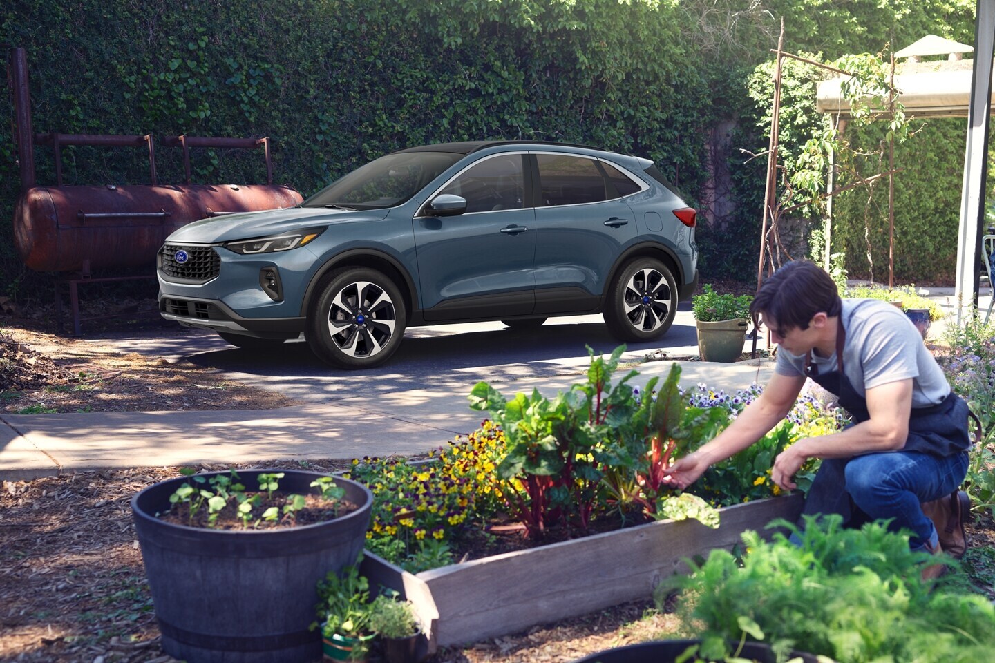 24_FRD_ESP_46641_plt_vpbl.jfif A Ford Escape parked by a community garden.