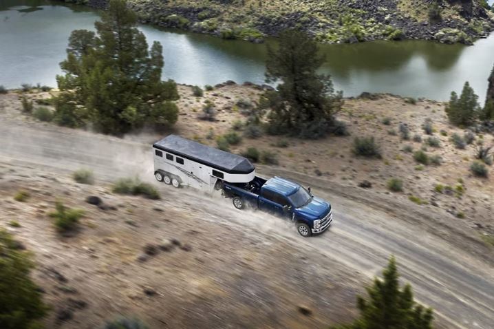 A Ford F-250 pulling a horse trailer down a mountain road.