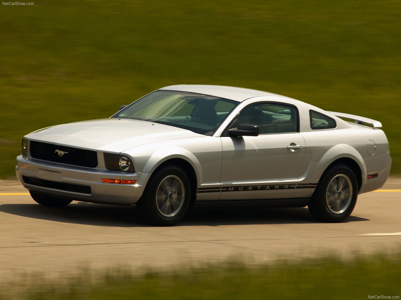 Ford-Mustang-2005-1280-02.jpg A silver 2005 Ford Mustang doing laps at a race track.