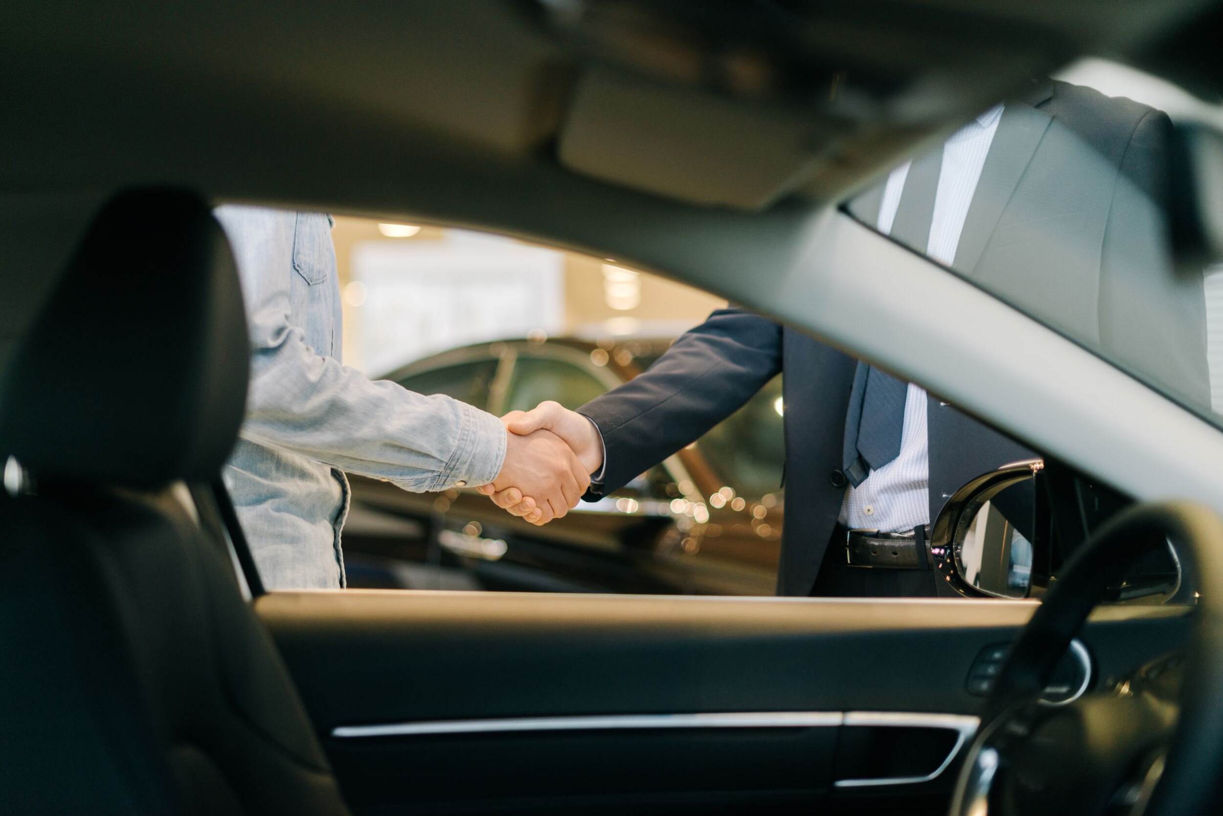 AdobeStock_343608923.jpeg Two people shaking hands after negotiating a deal on a used car.