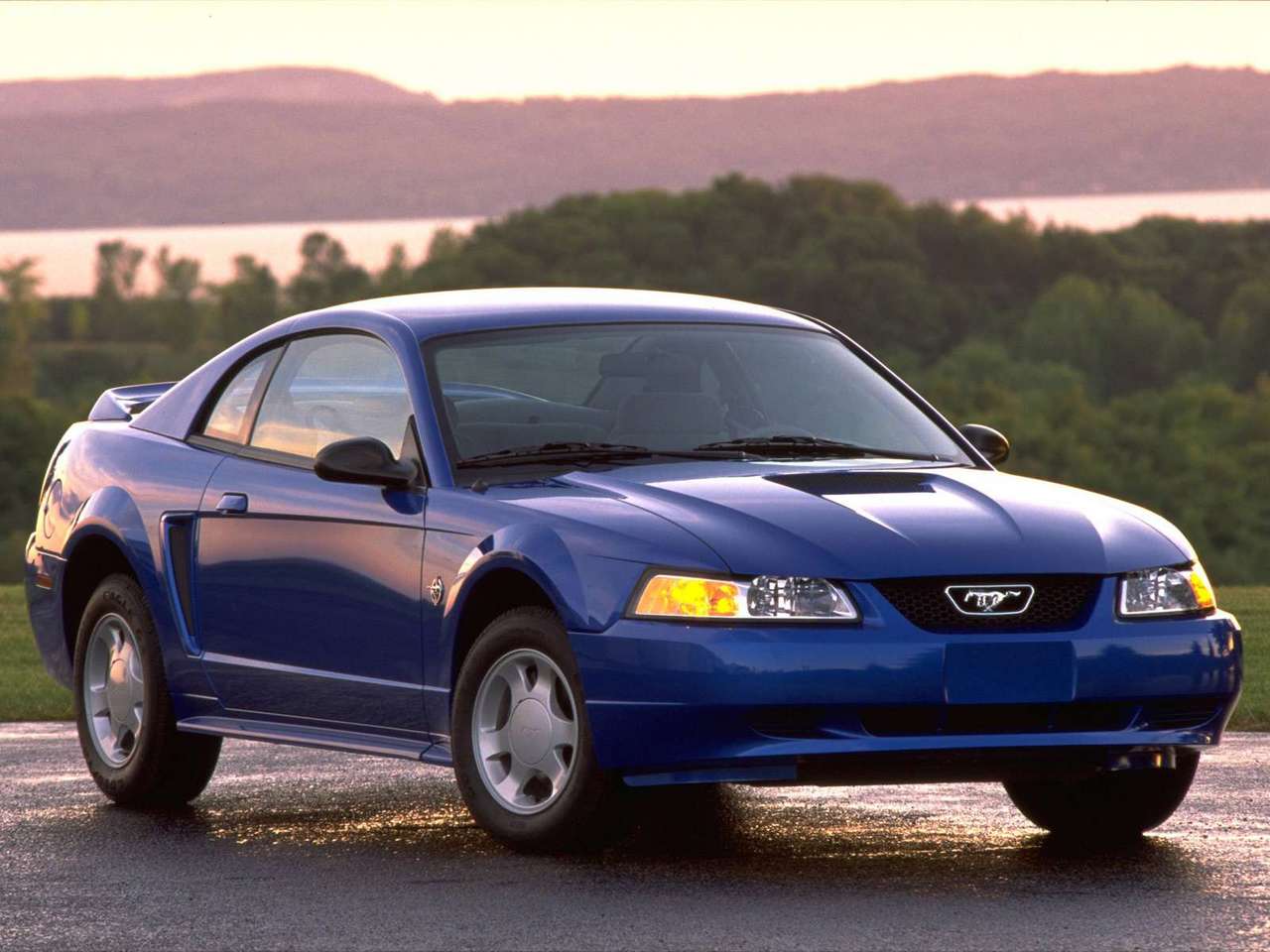 Ford-Mustang-1999-1280-01.jpg A blue 1999 Ford Mustang driving down a road.