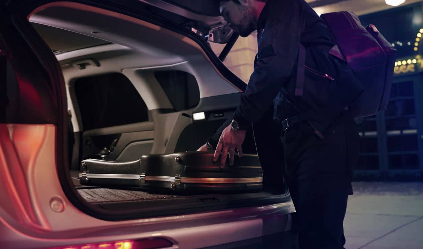 2022 Lincoln Corsair Storage Space Guy setting a guitar case into the trunk of a white 2022 Lincoln Corsair SUV