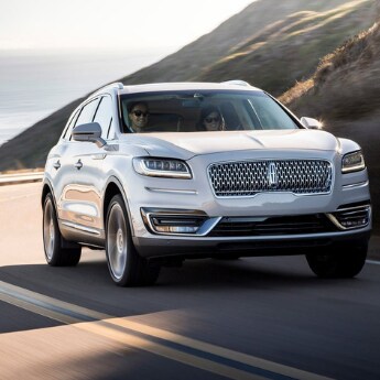2019 Lincoln Nautilus at Phil Long Lincoln.png A front side shot of a white 2019 Lincoln Nautilus driving around a
curvy road edging the small mountains with a beautiful view of the ocean on the
left