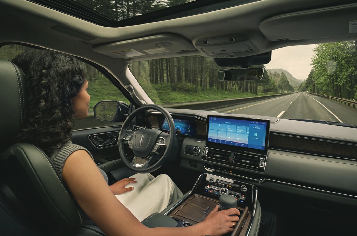 2023 - Lincoln - Navigator -4.PNG A woman driving a 2023 Lincoln Navigator, using the infotainment system