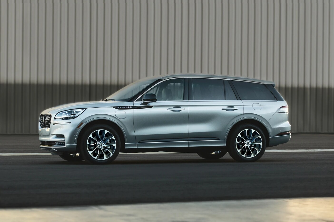 2022-Lincoln-Aviator-3.PNG A silver 2022 Lincoln Aviator Hybrid sits parked with a full profile view for the viewer.