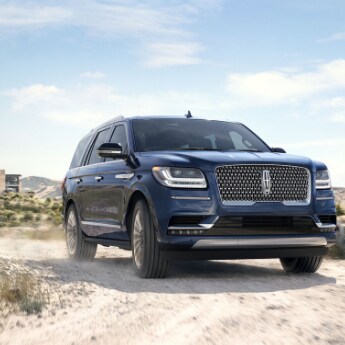 2019 Lincoln Navigator at Phil Long Lincoln.png The front passenger side angle of a blue 2019 Lincoln Navigator making a
turn around a sandy dirt road with a desert scenery in the background