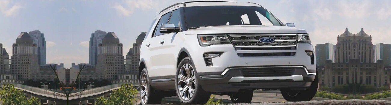 2019 Ford Explorer configurations in Raton Phil Long Ford.png Ground level view of the front of a white 2019 Ford Explorer with a city landscape in the distance