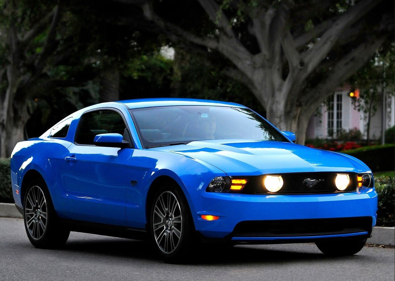 Ford-Mustang-2010-1280-02.jpg A Ford Mustang parked with large trees in the background.