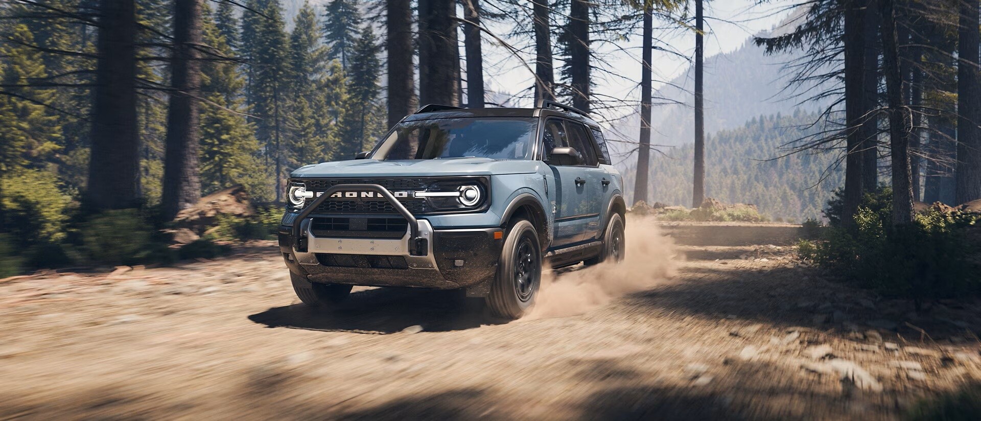 A grey Ford Bronco Sport driving on a dirt road in the mountains.