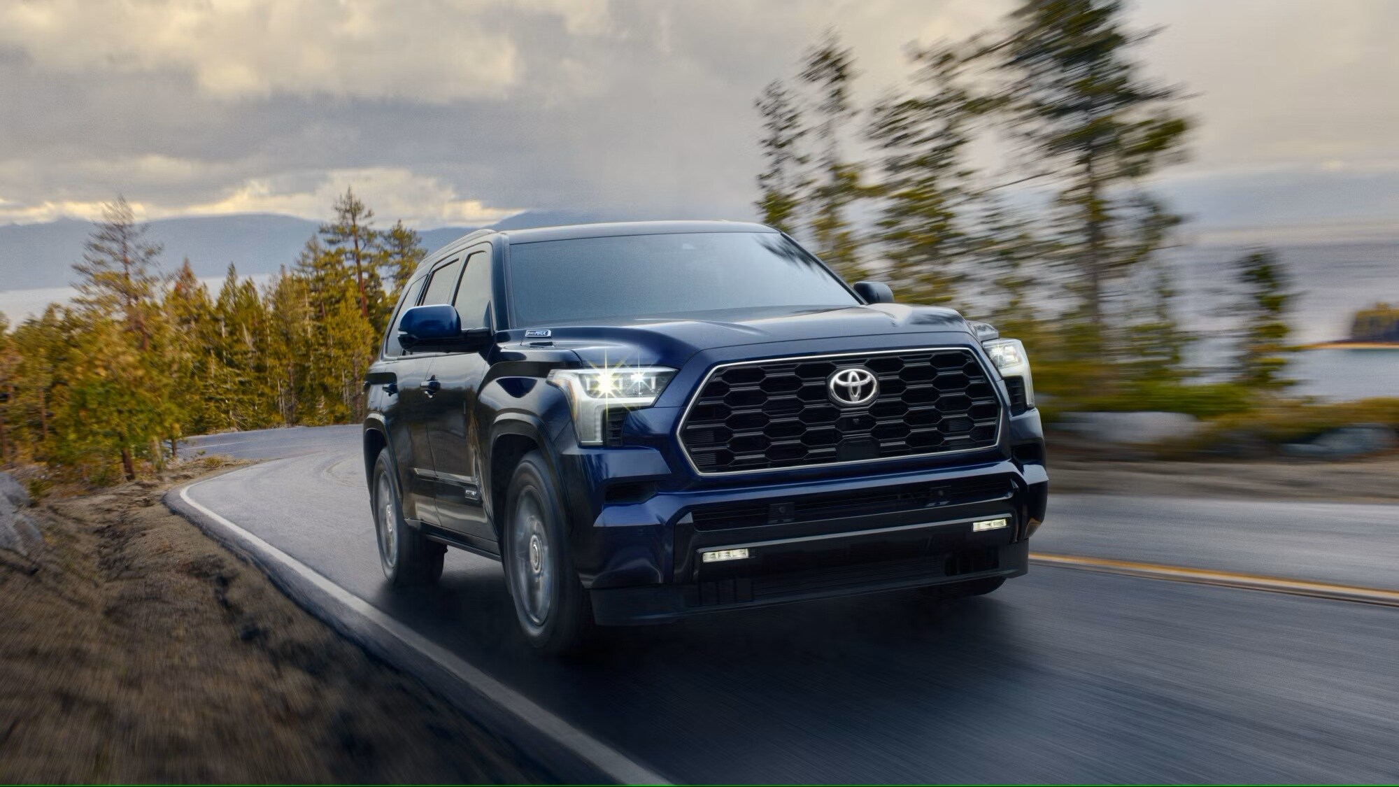 Metallic dark blue 2025 Toyota Sequoia driving up a mountain road.