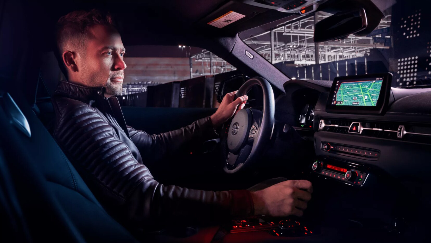 2022-Toyota-Supra-4.PNG A man driving a supra with the front seats, dashboard, and infotainment system visible