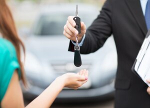 sales man handing over lease vehicle keys to woman