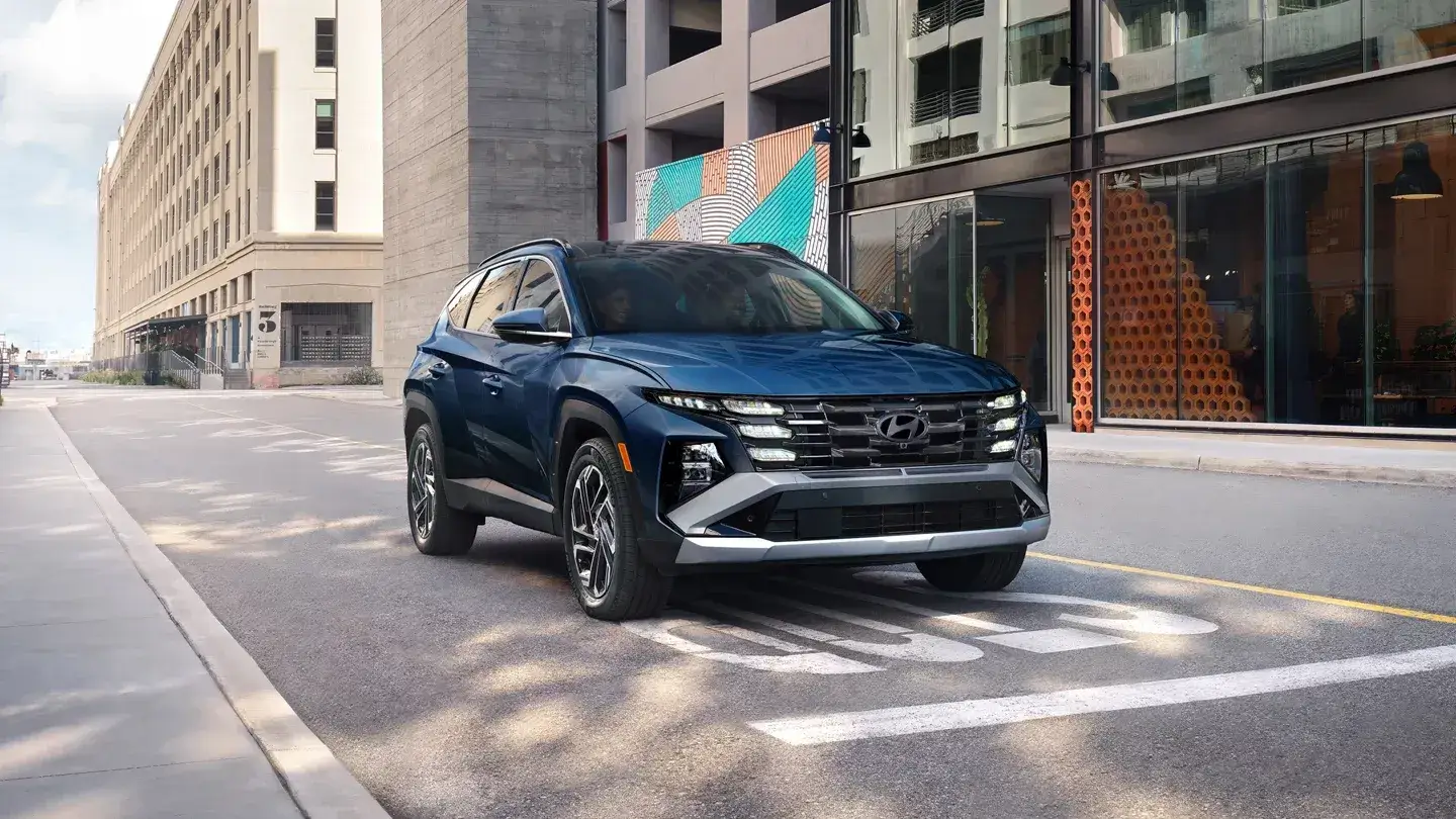 Blue Hyundai Tucson Limited with 19-inch alloy wheels on a city street, front three-quarter view