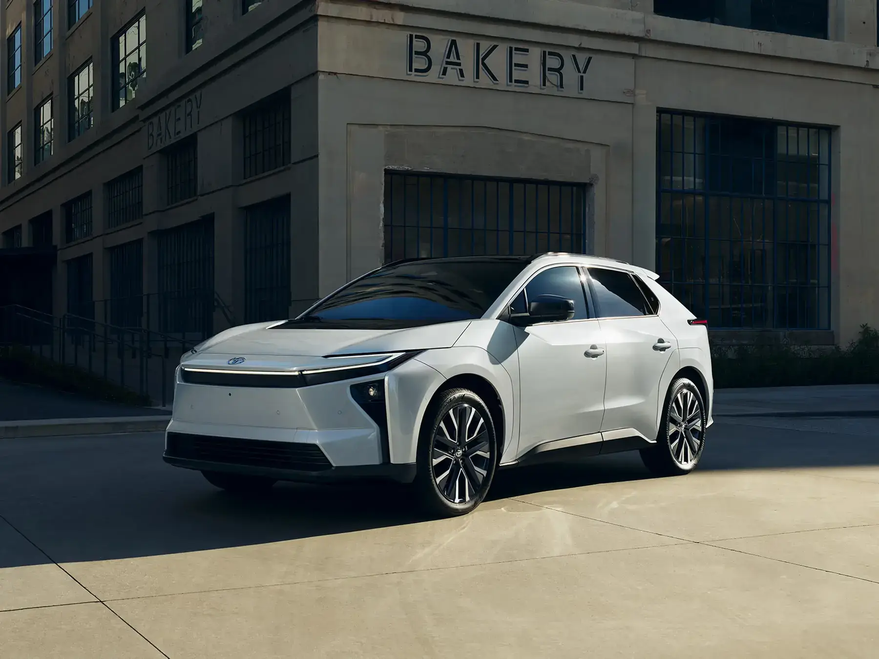 2027 Toyota bZ front three-quarter view showing C-shaped daytime running lights and hammerhead front end