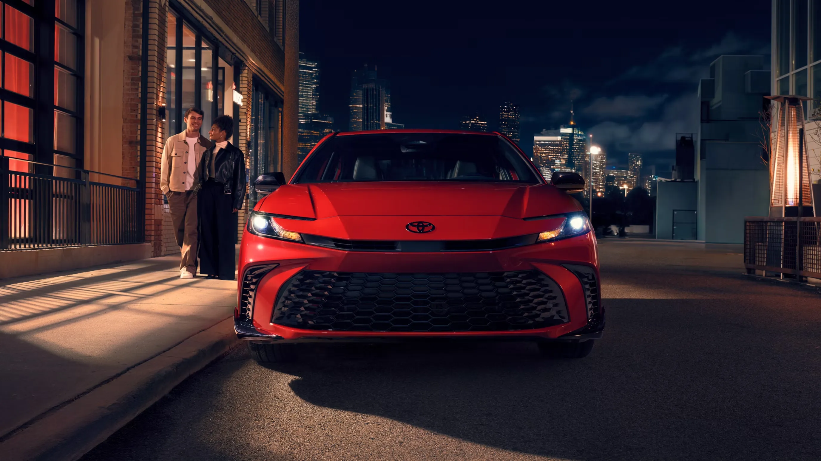 Front view of a red Toyota Camry showing the grille and C-shaped headlights