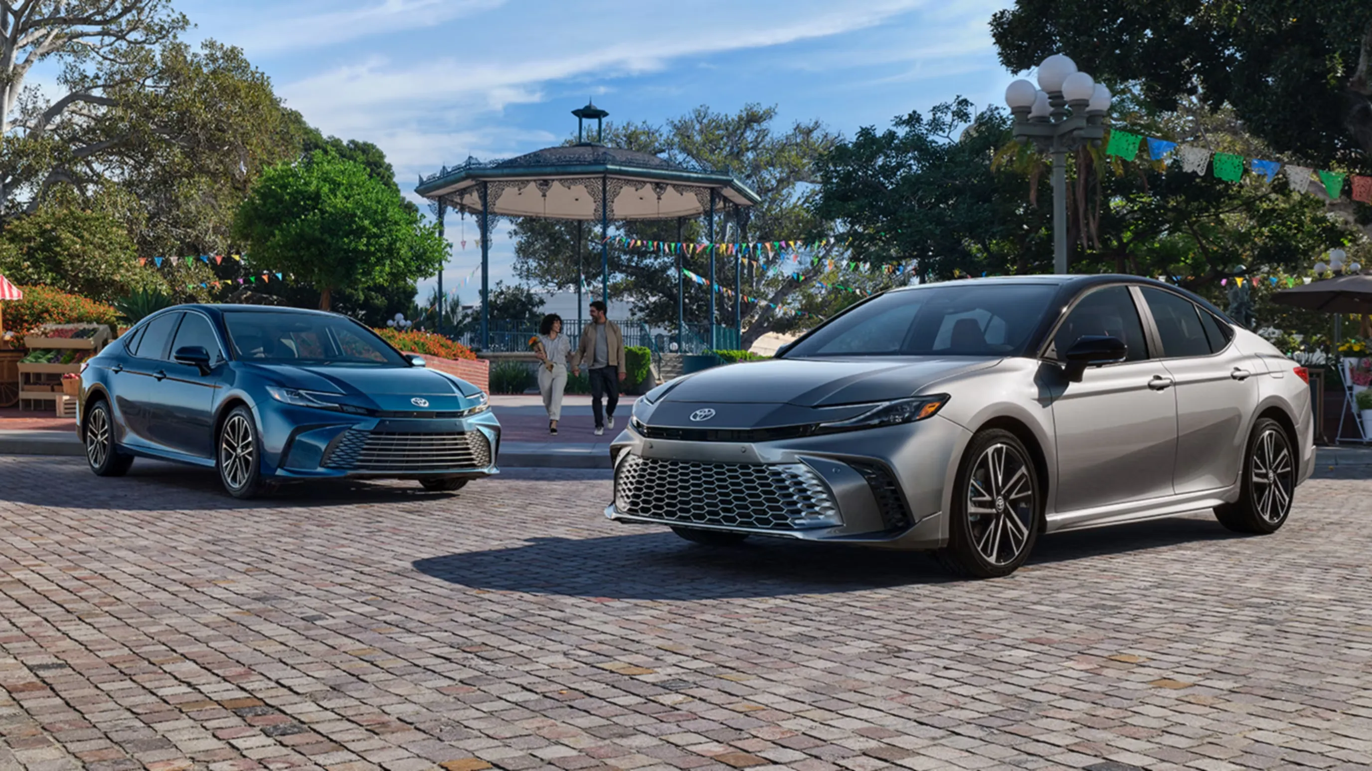 Two Toyota Camry hybrid sedans shown from the front three-quarter angle