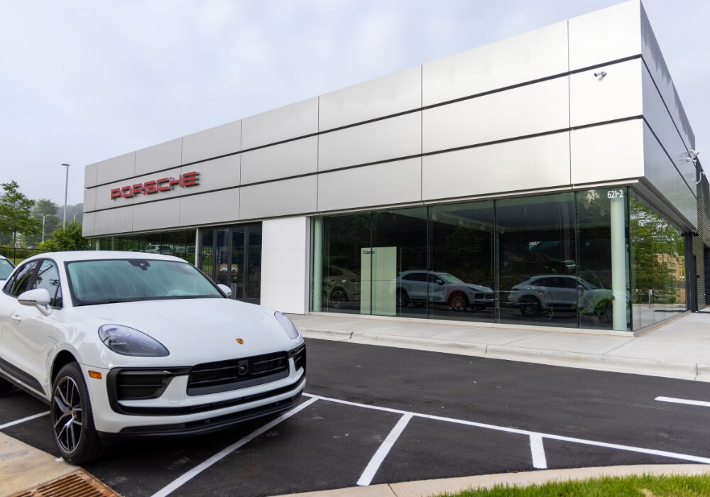 certified-porsche-cars-for-sale-asheville.png Porsche dealership storefront in Asheville, NC with a Porsche SUV parked in front