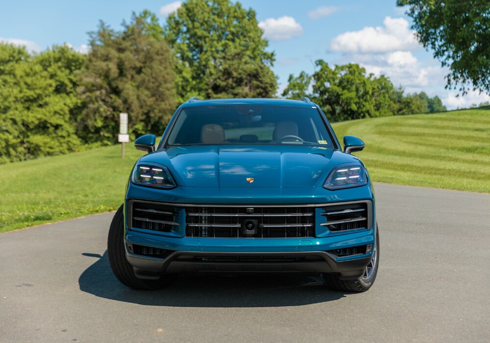 porsche-cayenne-for-sale-asheville.png Blue 2025 Porsche Cayenne parked in front of a big green field