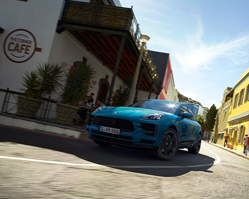 Blue Porsche Macan driving around a turn